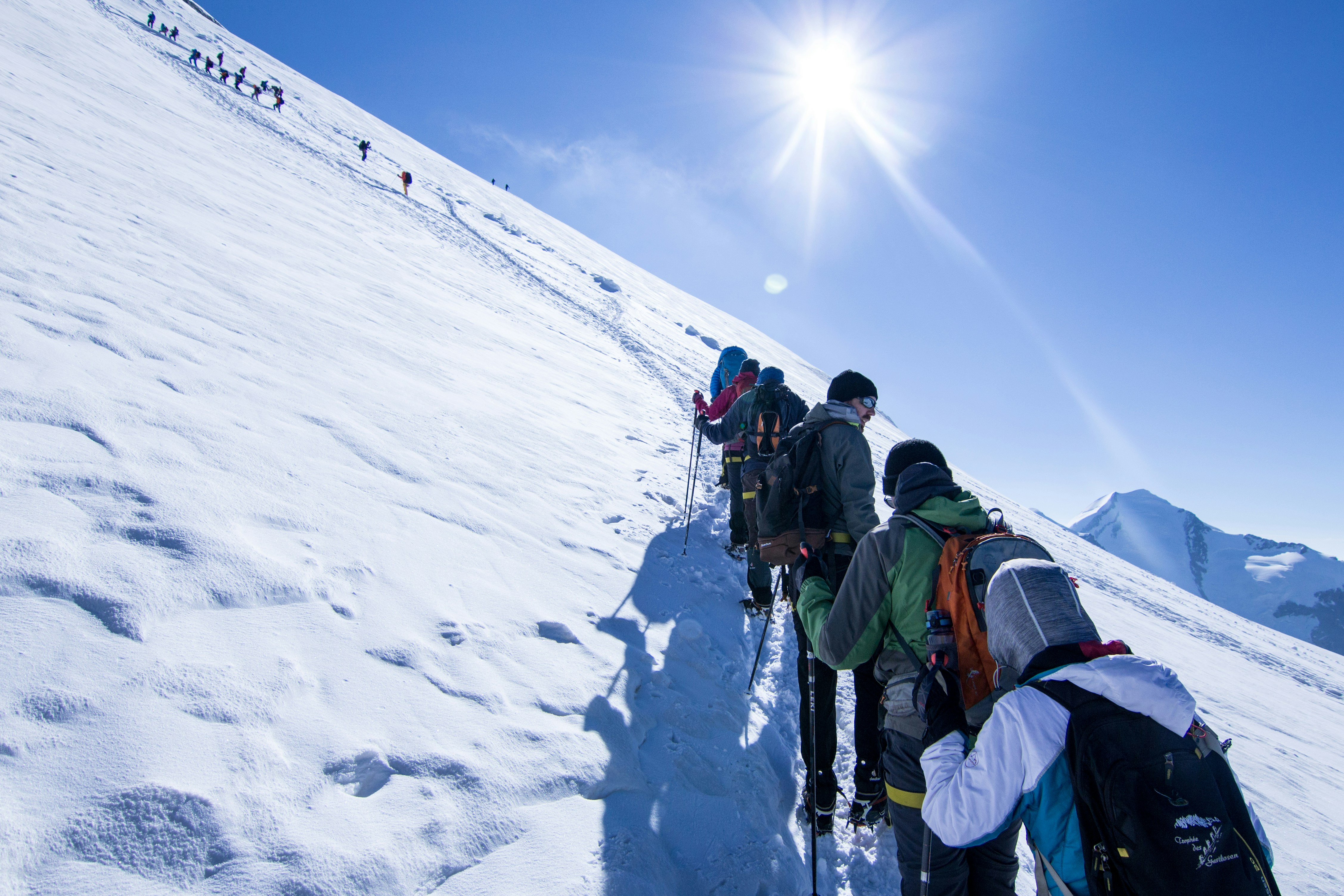  туристи з трекінговими палицями підіймаються на вершину взимку